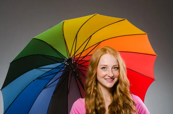 Woman holding colourful umbrella in studio — Stock Photo, Image