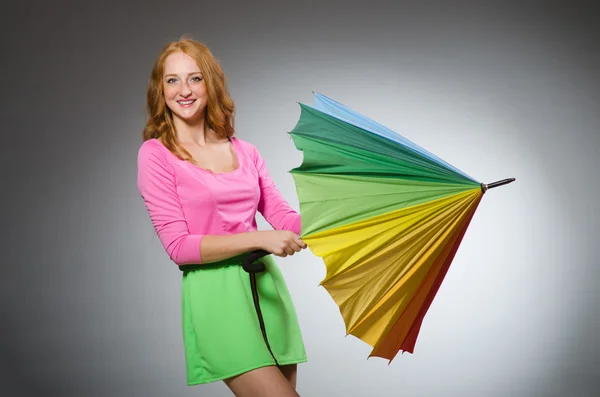 Woman holding colourful umbrella in studio — Stock Photo, Image