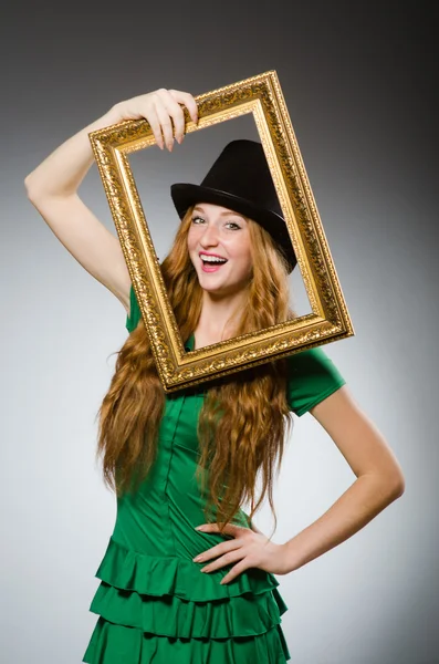 Mujer usando vestido verde sosteniendo marco de imagen — Foto de Stock