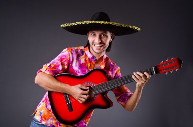 Gitarlı bir sombrero giyen adam.