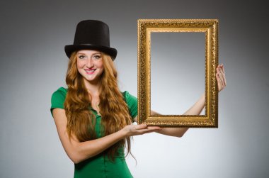 Elinde resim çerçevesi olan yeşil elbiseli bir kadın.