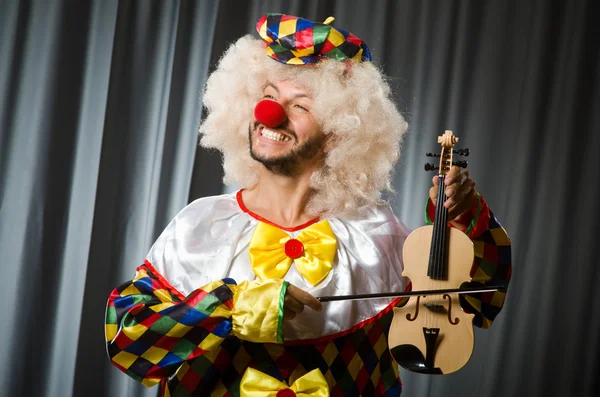 Lustiger Clown spielt Geige gegen Vorhang — Stockfoto