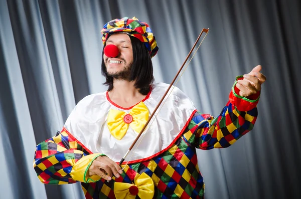 Divertido payaso plyaing violín contra cortina — Foto de Stock