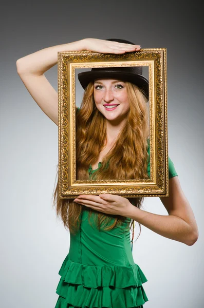 Woman wearing green dress holding picture frame — Stock Photo, Image