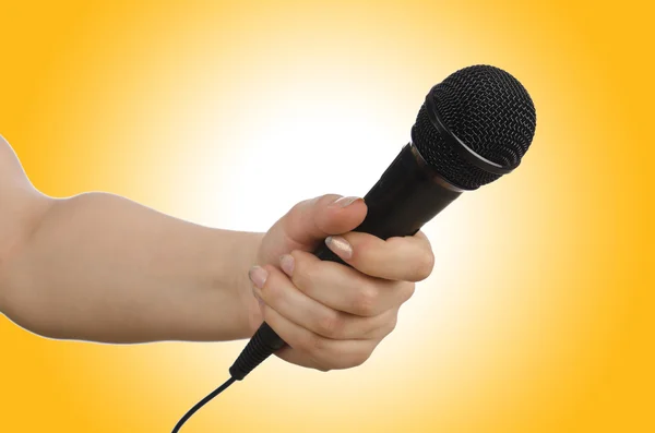 Hand with microphone on yellow — Stock Photo, Image