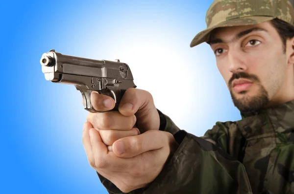 Солдат с пистолетом против градиента — стоковое фото