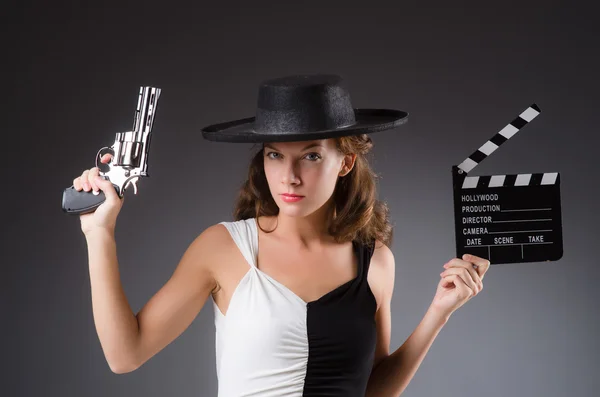 Girl with gun and clapperboard against the gradient — Stock Photo, Image