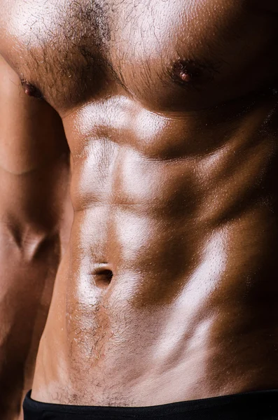 Muscular man posing in dark studio — Stock Photo, Image