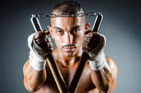 Uomo con i nunchaku sullo sfondo scuro — Foto Stock