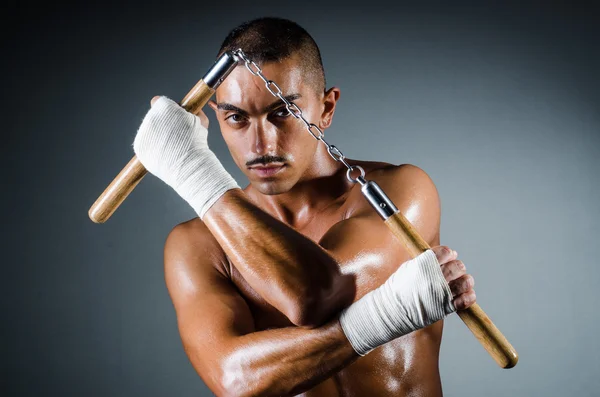 Man met nunchucks tegen de grijze achtergrond — Stockfoto