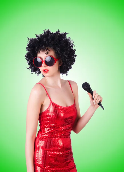 Pop ster met mic in rode jurk tegen het verloop — Stockfoto