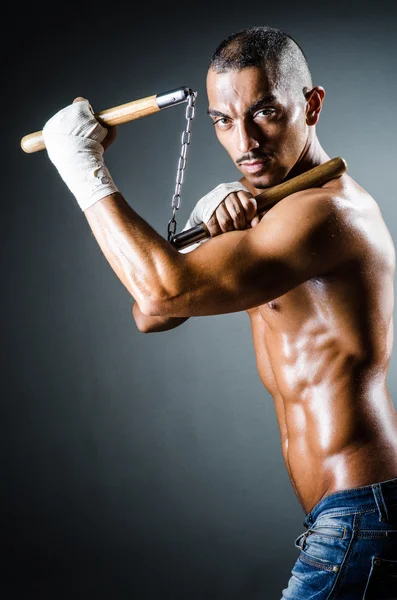 Man with nunchucks against grey background — Stock Photo, Image