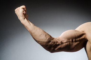 Kaslı adam karanlık stüdyoda poz veriyor.