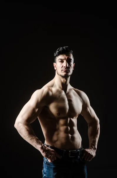 Muscular man posing in dark studio — Stock Photo, Image