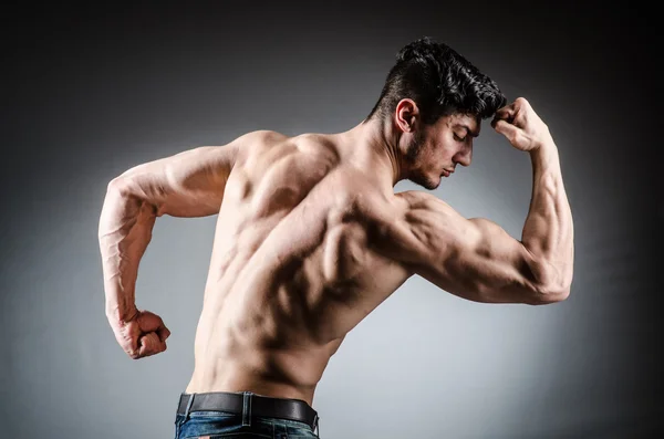 Muscular man posing in dark studio — Stock Photo, Image