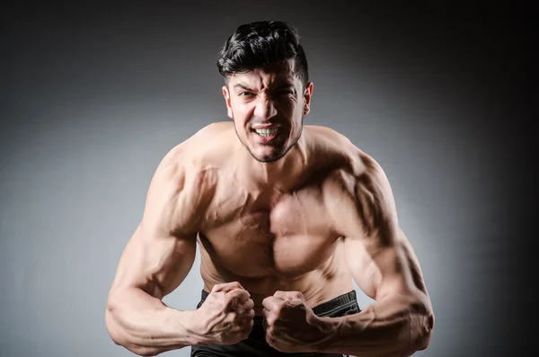 Muscular man posing in dark studio — Stock Photo, Image