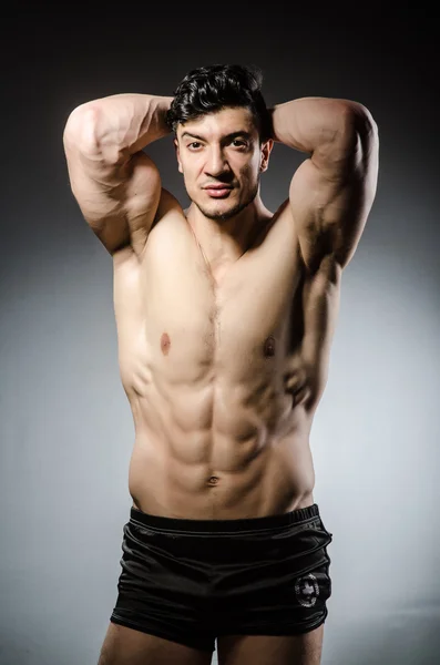 Muscular man posing in dark studio — Stock Photo, Image