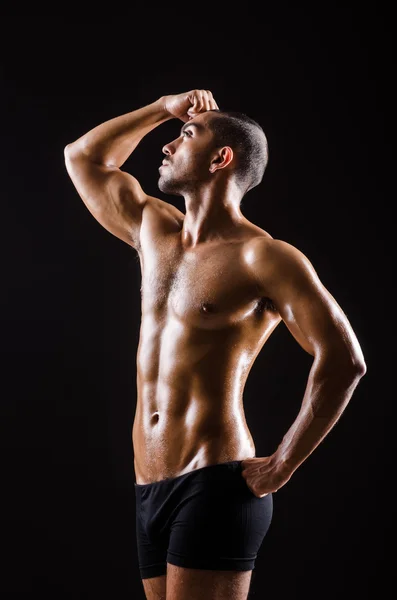 Uomo muscolare in posa in studio scuro — Foto Stock