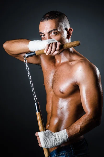 Uomo con i nunchaku sullo sfondo scuro — Foto Stock