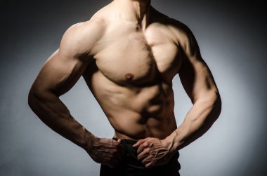 Kaslı adam gri arka plan üzerinde poz