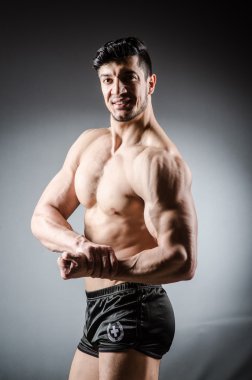 Kaslı adam gri arka plan üzerinde poz