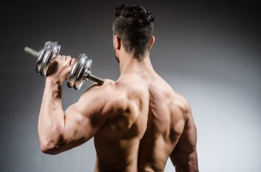 Vücut geliştirmeci dumbbells ile gri arka plan üzerinde yırtık kas