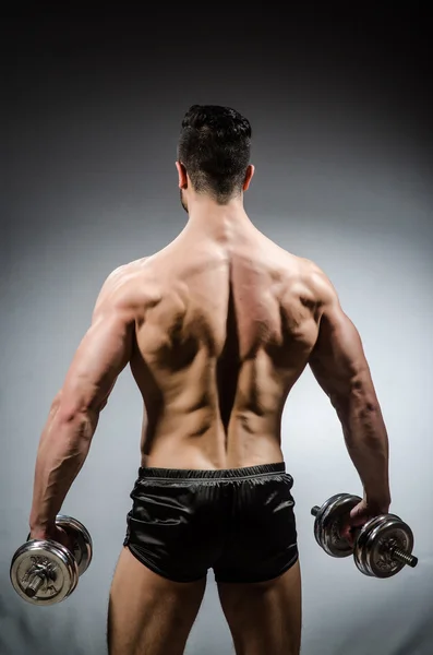 Bodybuilder déchiré musculaire avec haltères sur fond gris — Photo