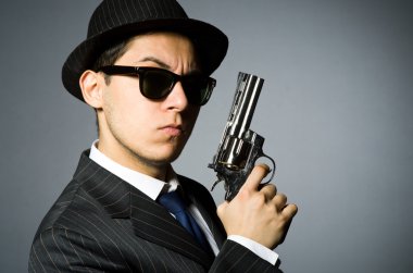 Genç adam elinde silah gri izole klasik çizgili kostüm