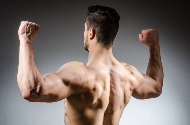 Kaslı adam karanlık stüdyoda poz veriyor.