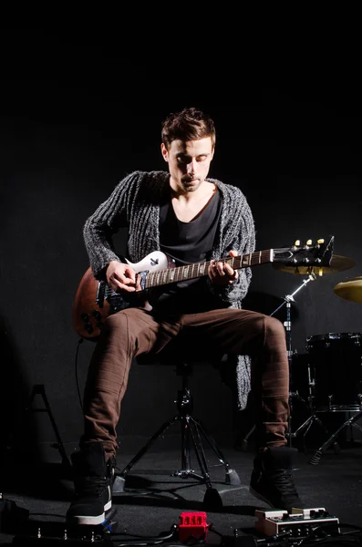 Homem tocando guitarra no quarto escuro — Fotografia de Stock