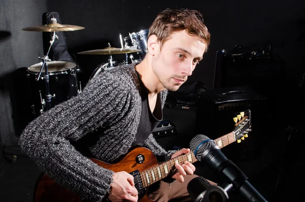 Hombre tocando la guitarra en habitación oscura — Foto de Stock