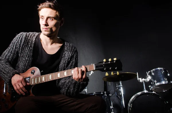 Hombre tocando la guitarra en habitación oscura — Foto de Stock