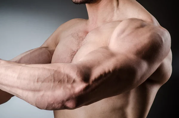 Muscular man posing in dark studio — Stock Photo, Image