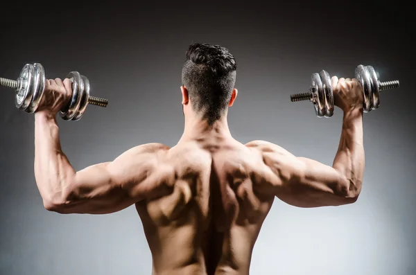 Muscular fisiculturista rasgado com halteres — Fotografia de Stock