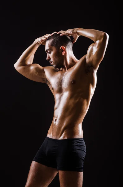 Muscular man posing in dark studio — Stock Photo, Image