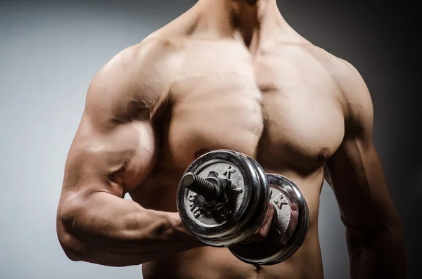 Muscular desgarrado culturista con mancuernas sobre fondo gris —  Fotos de Stock