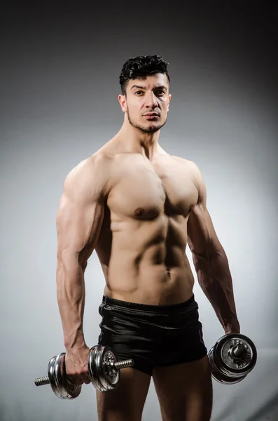 Muscular ripped bodybuilder with dumbbells on grey background — Stock Photo, Image