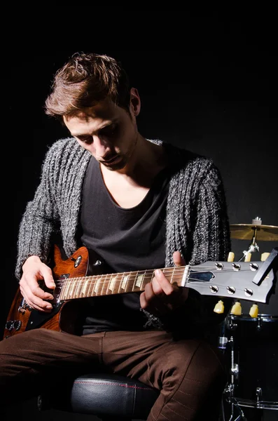 Человек играет на гитаре в темной комнате — стоковое фото