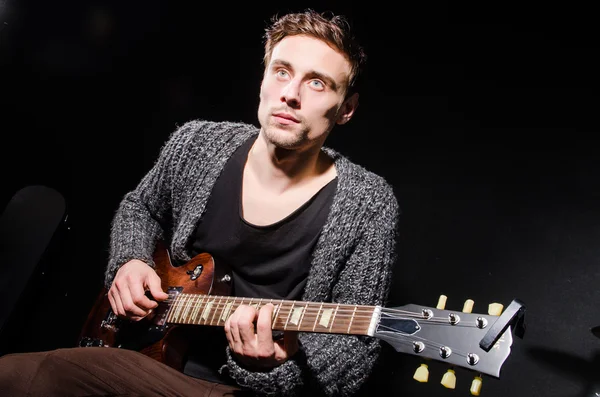 Hombre tocando la guitarra en habitación oscura —  Fotos de Stock