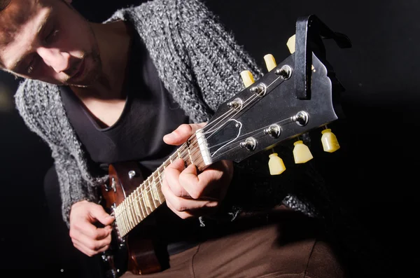 Mężczyzna gra na gitarze w ciemnym pokoju — Zdjęcie stockowe