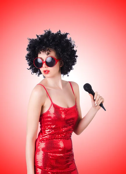 Pop ster met mic in rode jurk tegen het verloop — Stockfoto