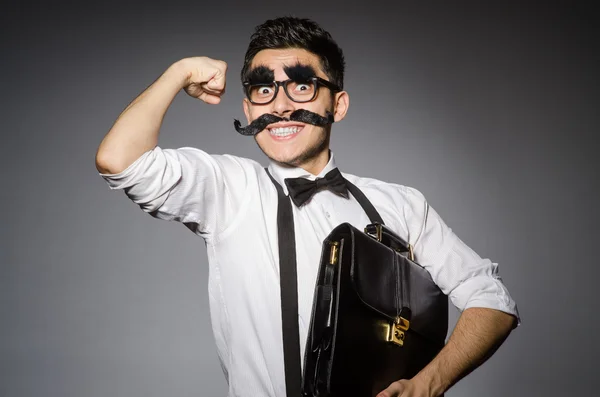 Jovem com bigode falso segurando caso isolado em cinza — Fotografia de Stock