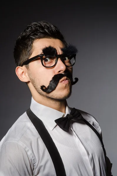 Młody człowiek z fałszywych wąsy na szarym tle — Zdjęcie stockowe