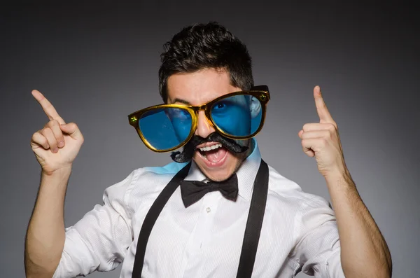 Junger Mann mit falschem Schnurrbart und großer Sonnenbrille isoliert auf grau — Stockfoto