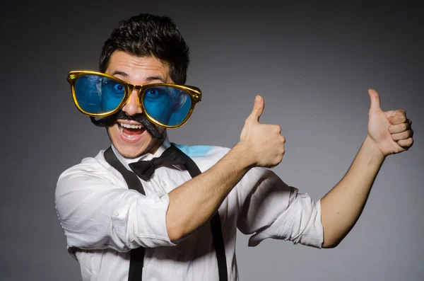 Jeune homme avec une fausse moustache et de grandes lunettes de soleil isolées sur gris — Photo