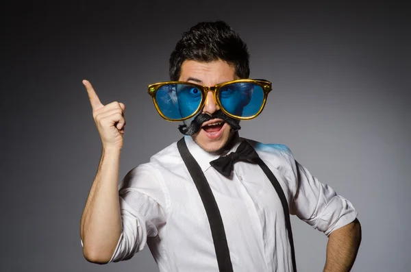 Hombre joven con bigote falso y gafas de sol grandes aisladas en gris —  Fotos de Stock