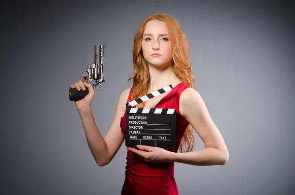 Krásná mladá dívka v červených šatech s pistolí izolované Grey — Stock fotografie