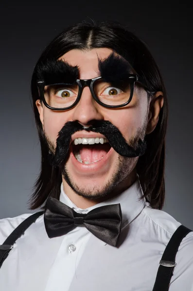 Jovem com bigode falso e sobrancelhas isoladas em cinza — Fotografia de Stock