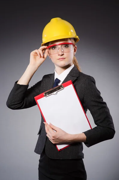 Female engineer with helmet and paper isolated on gray — Stock Photo, Image