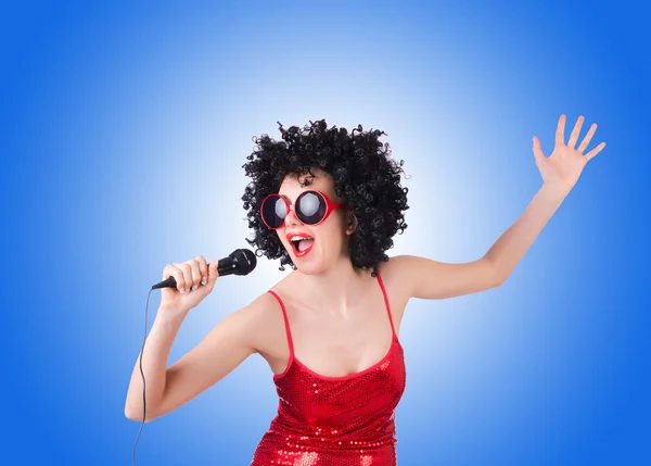 Pop star with mic in red dress against gradient — Stock Photo, Image